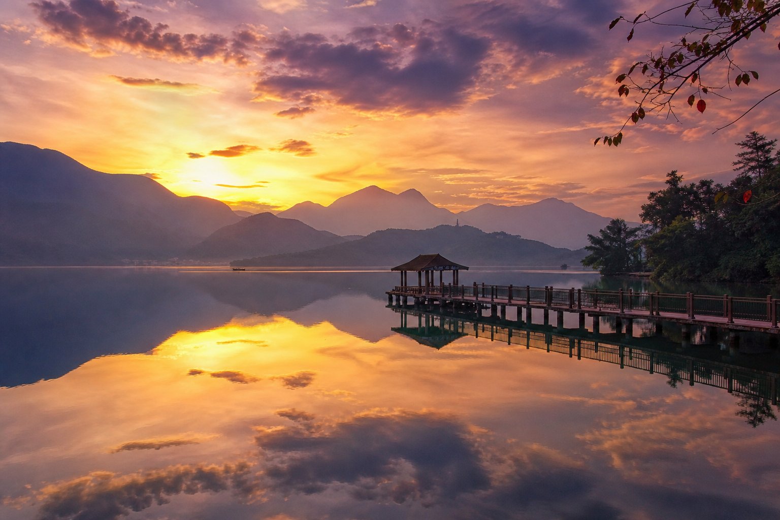 日月潭秋天夕陽,湖面如鏡倒映金色霞光與層層山巒