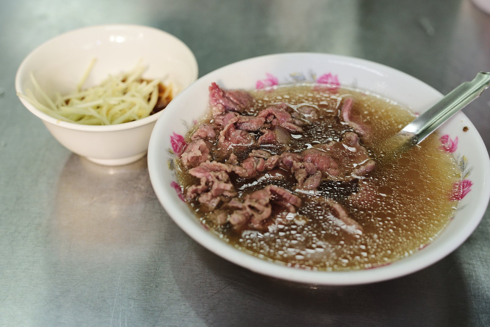 現切溫體牛肉淋上滾燙高湯的台南牛肉湯,清晨攤位木桌晨光